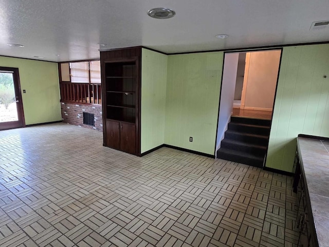 spare room featuring a fireplace, a healthy amount of sunlight, and wood walls