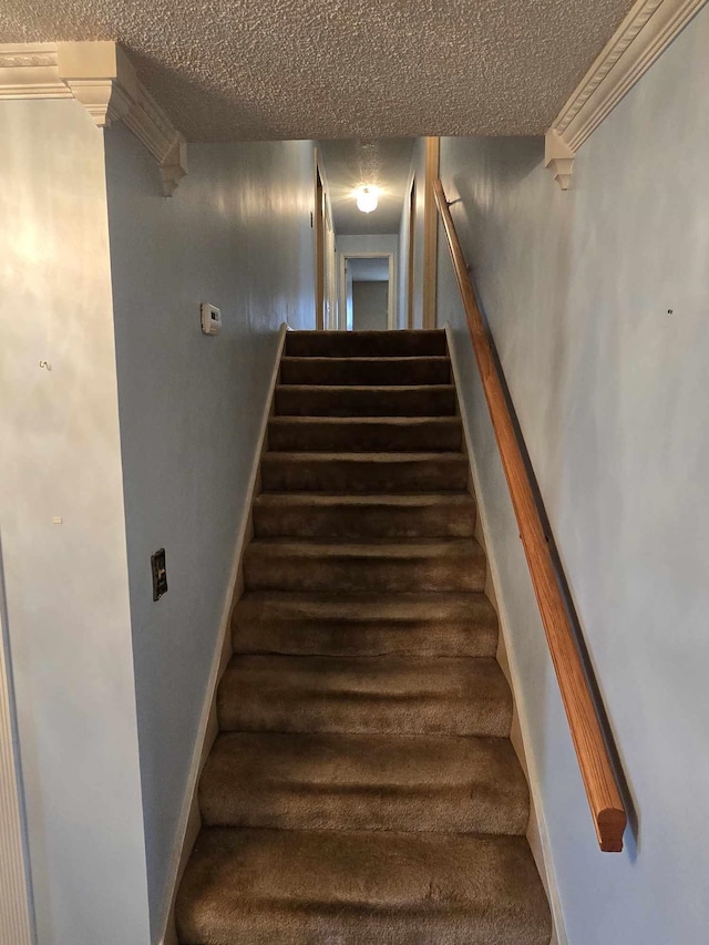 stairway featuring a textured ceiling