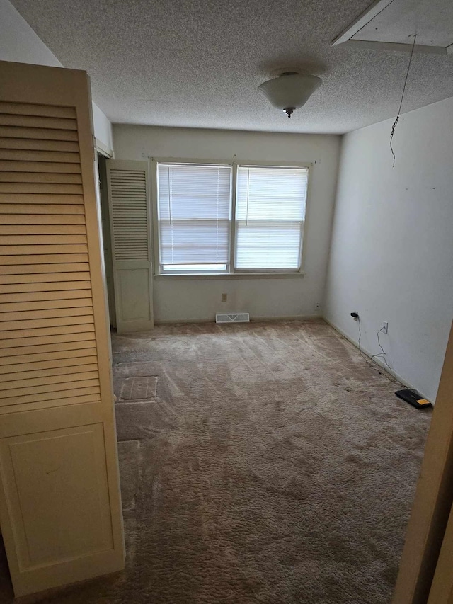 carpeted spare room featuring a textured ceiling