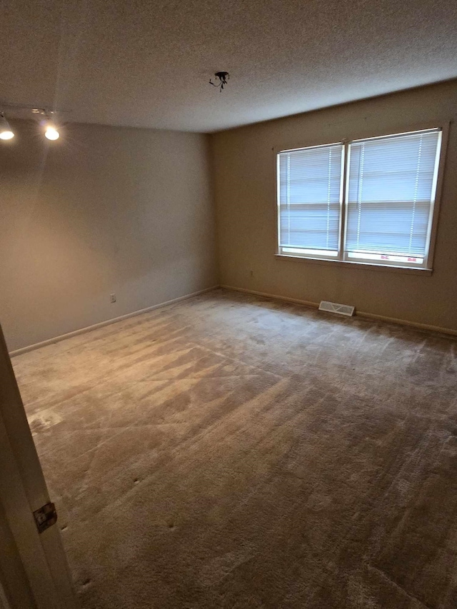 carpeted spare room featuring a textured ceiling