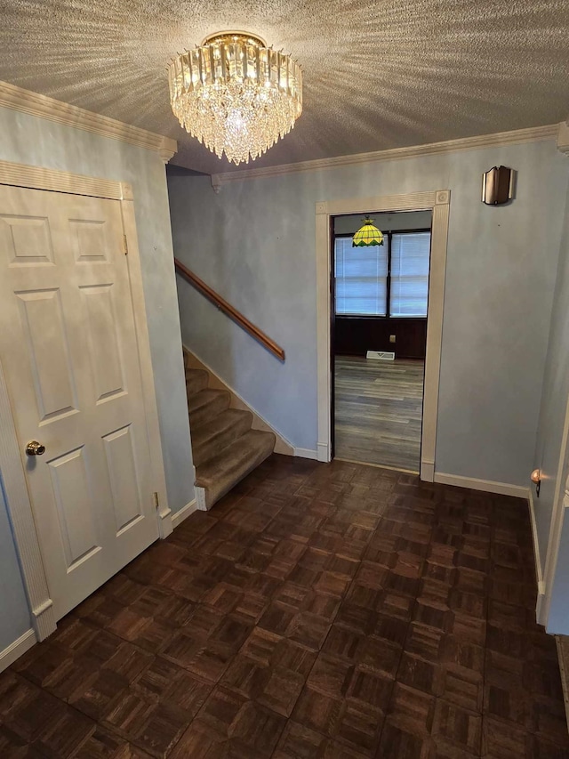 foyer featuring ornamental molding, a textured ceiling, and dark parquet flooring