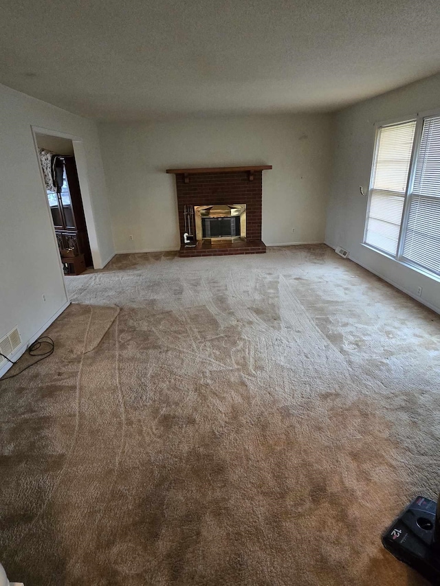 unfurnished living room featuring light colored carpet, a fireplace, and a textured ceiling