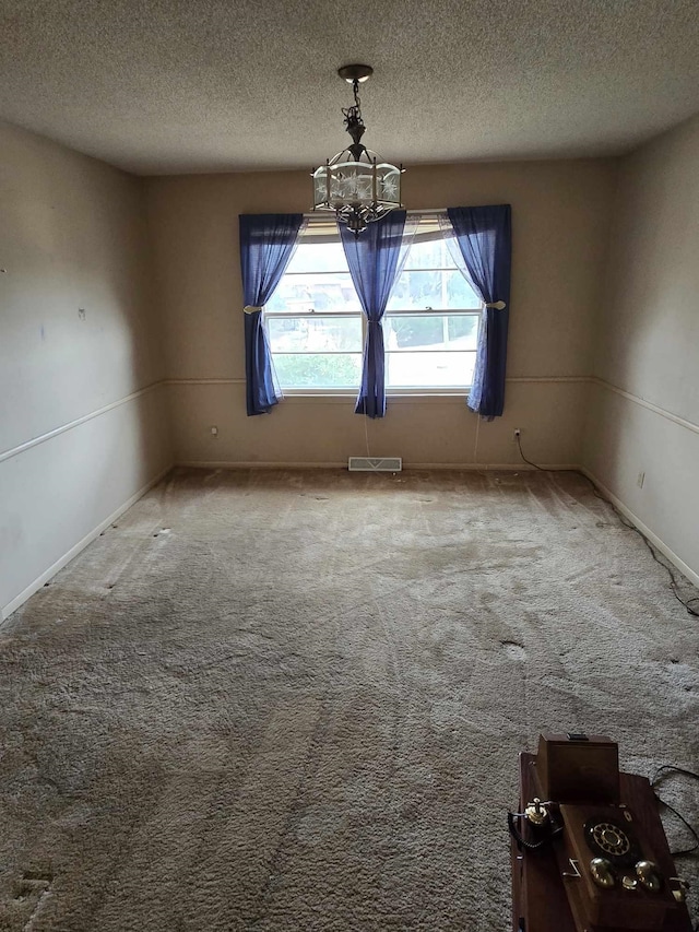 unfurnished room featuring carpet, a notable chandelier, and a textured ceiling