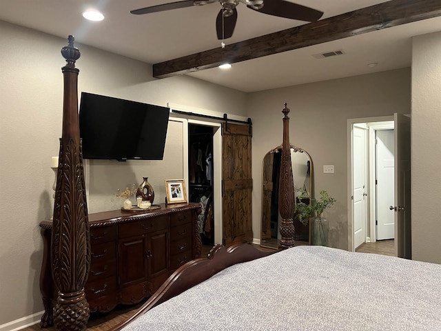 bedroom featuring a closet, beam ceiling, a barn door, and ceiling fan