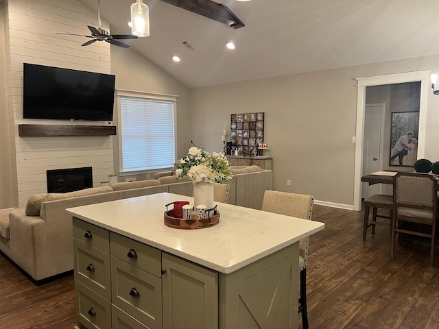 kitchen featuring light stone counters, vaulted ceiling, dark hardwood / wood-style floors, a kitchen island, and a fireplace