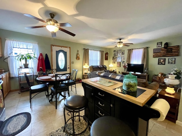 kitchen with a kitchen island, a breakfast bar area, ceiling fan, and light tile patterned floors