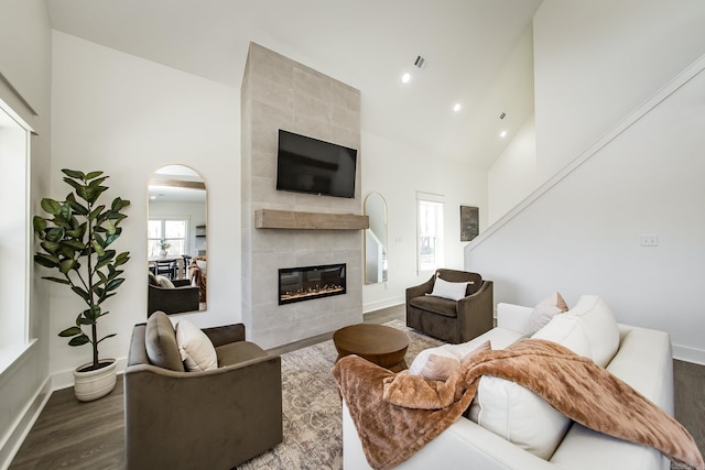 living room with dark hardwood / wood-style flooring, a fireplace, and high vaulted ceiling