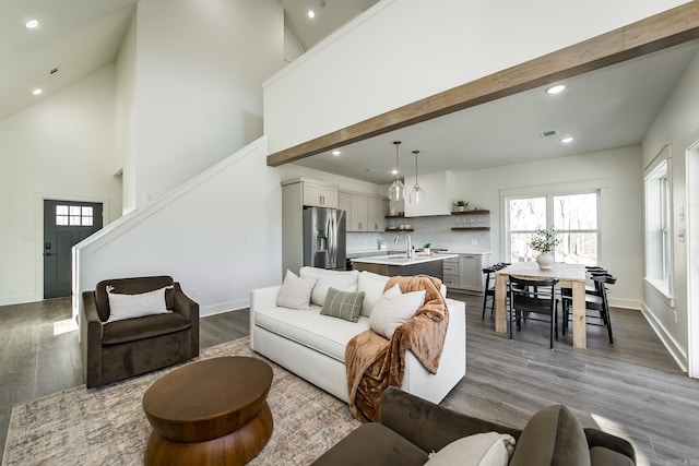 living room featuring hardwood / wood-style flooring, high vaulted ceiling, and beamed ceiling