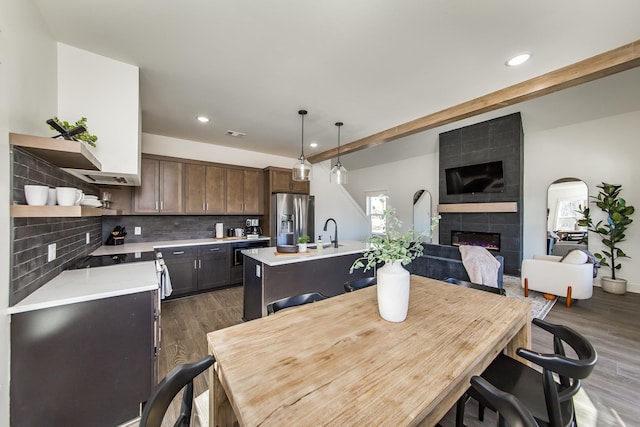 dining space with dark hardwood / wood-style floors, a fireplace, sink, and beam ceiling