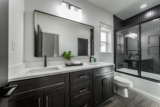 full bathroom with hardwood / wood-style flooring, vanity, toilet, and combined bath / shower with glass door