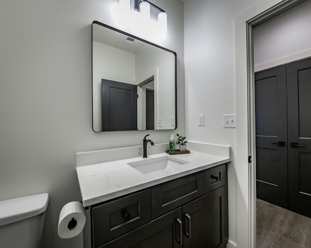 bathroom with vanity, hardwood / wood-style flooring, and toilet