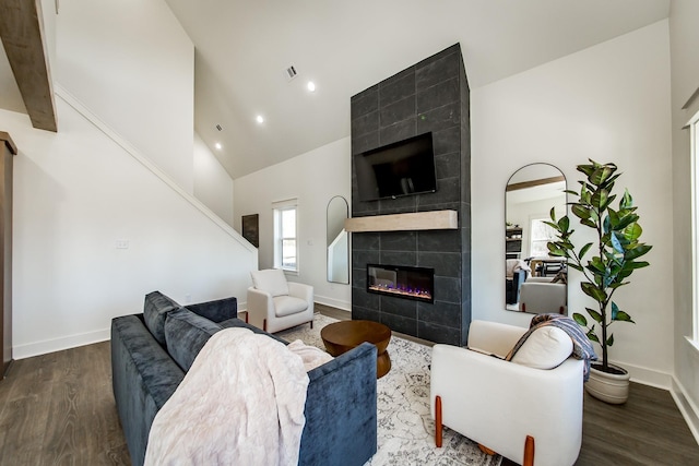 living room featuring dark wood-type flooring, a fireplace, and high vaulted ceiling