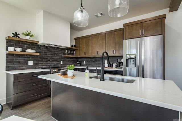 kitchen featuring pendant lighting, sink, light stone counters, stainless steel refrigerator with ice dispenser, and dark brown cabinets