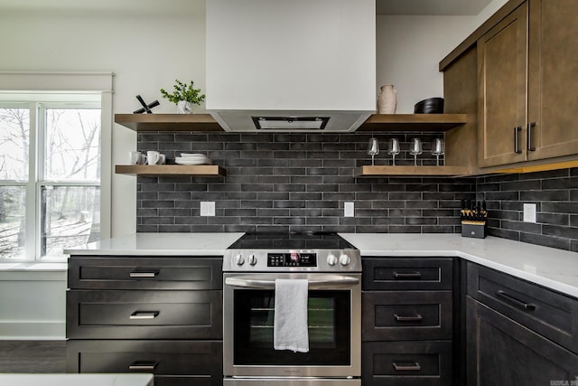 kitchen with dark brown cabinets, exhaust hood, backsplash, and electric stove