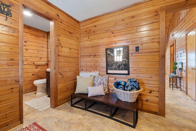 living area featuring a textured ceiling and wooden walls