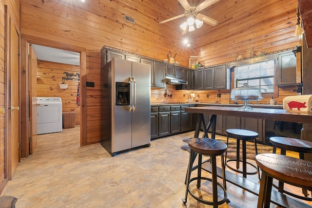 kitchen featuring wood walls, washer / clothes dryer, dark brown cabinetry, stainless steel refrigerator with ice dispenser, and wooden ceiling