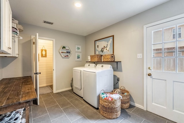 washroom featuring cabinets, washing machine and dryer, and dark tile patterned flooring