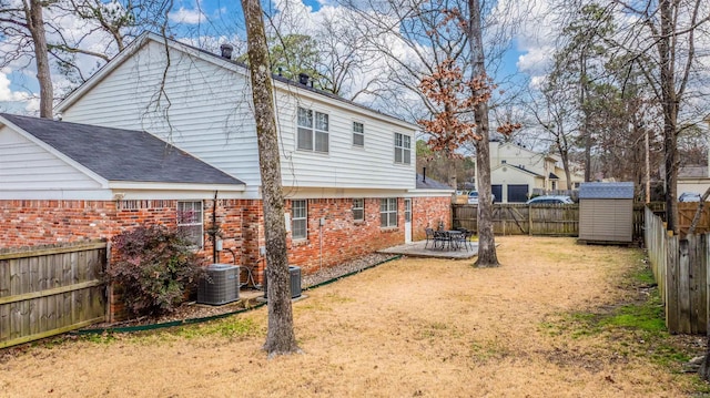 rear view of property featuring a shed, a yard, central AC, and a patio