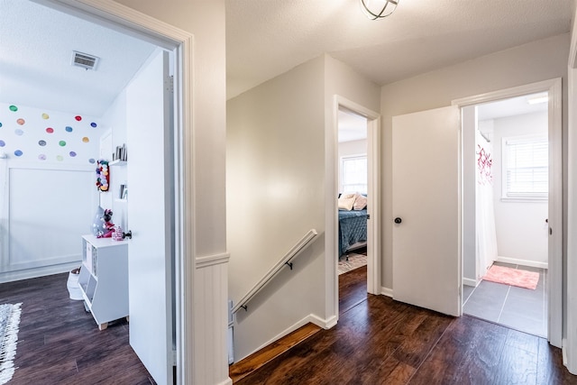 corridor featuring a healthy amount of sunlight, dark hardwood / wood-style floors, and a textured ceiling