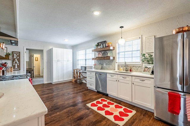 kitchen with appliances with stainless steel finishes, dark hardwood / wood-style floors, decorative light fixtures, white cabinetry, and sink