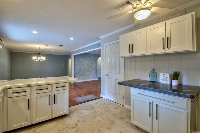 kitchen featuring ornamental molding, white cabinets, pendant lighting, and ceiling fan with notable chandelier