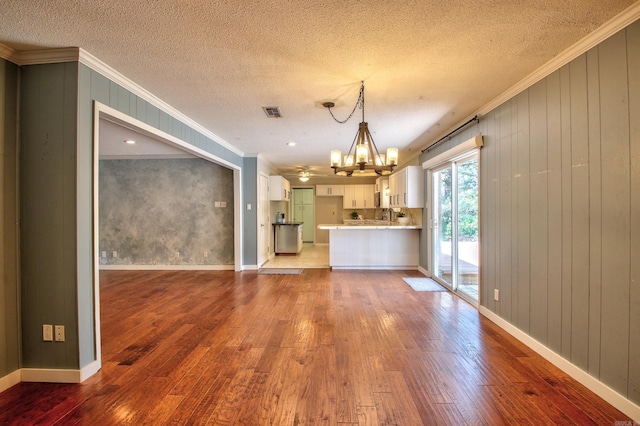 interior space with a textured ceiling, ornamental molding, a chandelier, and wood-type flooring