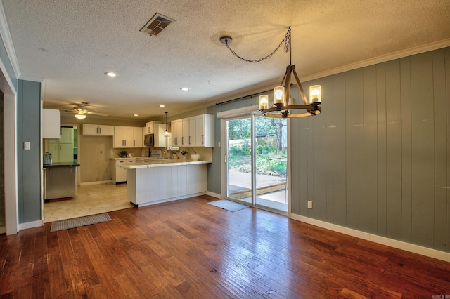 kitchen featuring light hardwood / wood-style flooring, hanging light fixtures, crown molding, white cabinetry, and kitchen peninsula