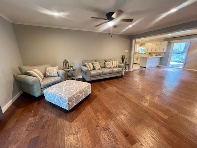 living room with ornamental molding, dark wood-type flooring, and ceiling fan