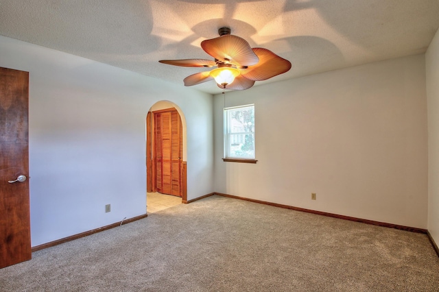 carpeted spare room featuring a textured ceiling and ceiling fan