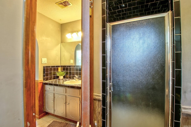 bathroom featuring a shower with door, tile patterned flooring, tasteful backsplash, and vanity