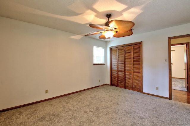 unfurnished bedroom featuring a textured ceiling, a closet, carpet flooring, and ceiling fan