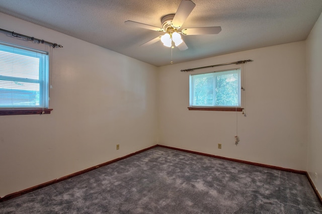 spare room with a textured ceiling, dark colored carpet, and ceiling fan