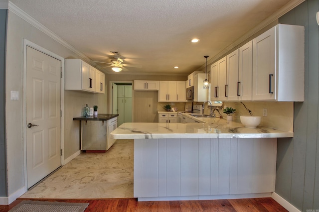 kitchen with kitchen peninsula, decorative light fixtures, light hardwood / wood-style floors, sink, and white cabinets