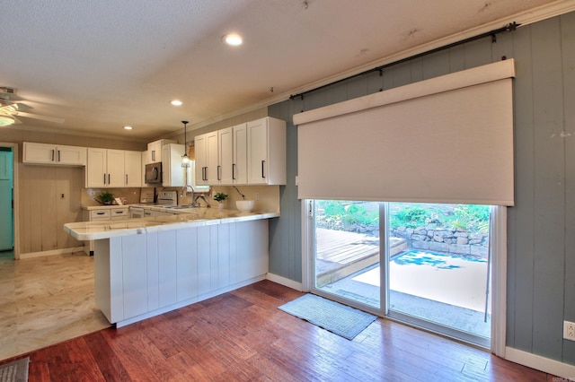 kitchen with light hardwood / wood-style flooring, sink, white cabinetry, decorative light fixtures, and kitchen peninsula