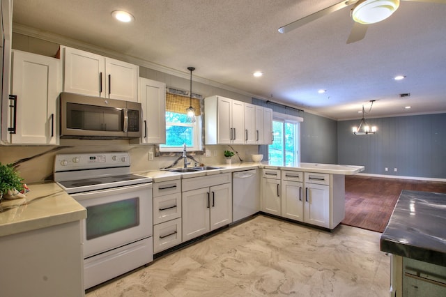 kitchen with white appliances, sink, white cabinets, and decorative light fixtures