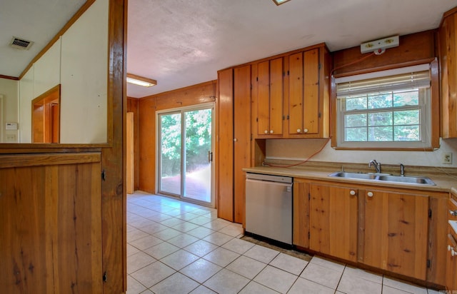 kitchen with a healthy amount of sunlight, dishwasher, sink, and light tile patterned floors