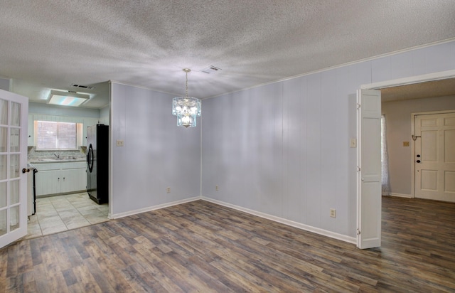 empty room featuring ornamental molding, sink, a notable chandelier, and light hardwood / wood-style flooring