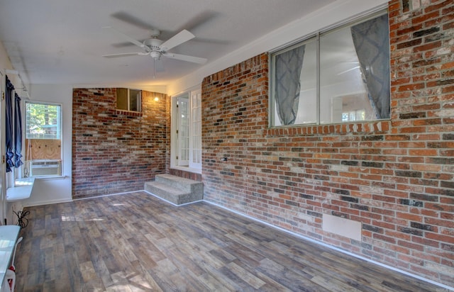 spare room with cooling unit, brick wall, wood-type flooring, and ceiling fan