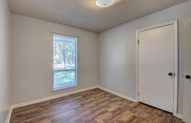 unfurnished room with dark hardwood / wood-style flooring and a textured ceiling