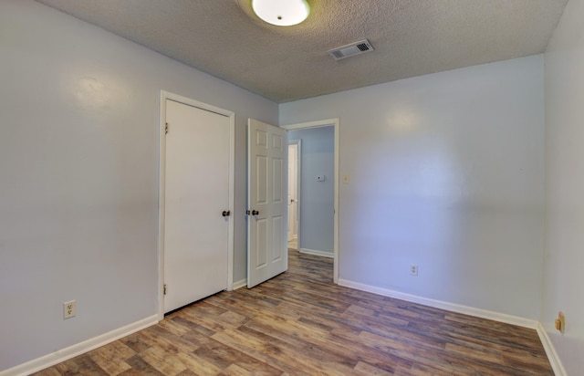 unfurnished room with hardwood / wood-style floors and a textured ceiling