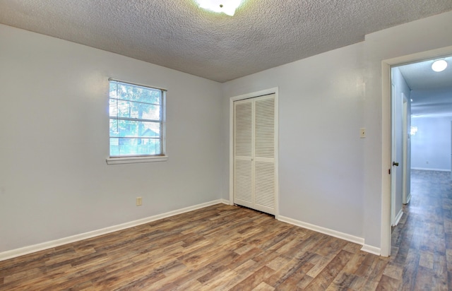 unfurnished bedroom with hardwood / wood-style floors, a textured ceiling, and a closet