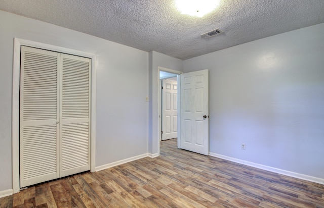 unfurnished bedroom featuring hardwood / wood-style floors, a textured ceiling, and a closet