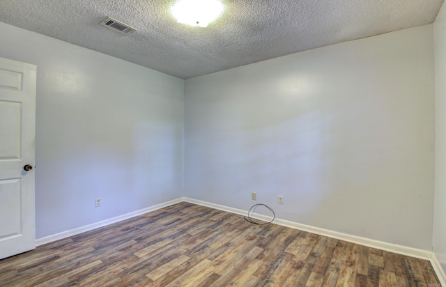 empty room featuring dark hardwood / wood-style floors and a textured ceiling