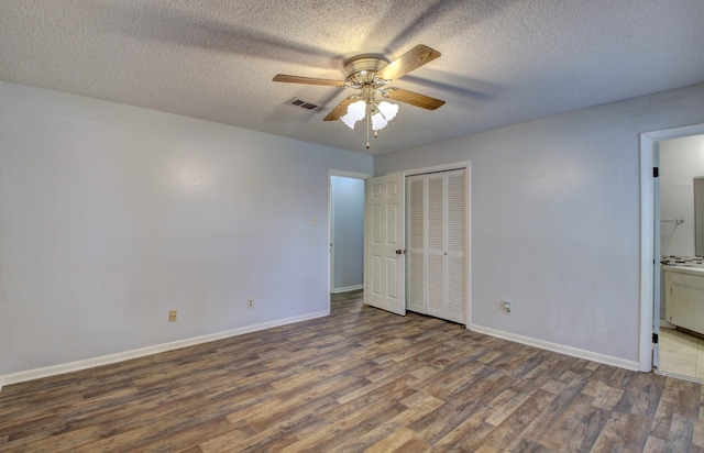 unfurnished bedroom featuring ceiling fan, a closet, dark hardwood / wood-style flooring, and a textured ceiling