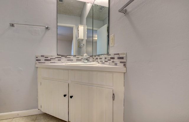 bathroom with vanity, tile patterned flooring, and backsplash