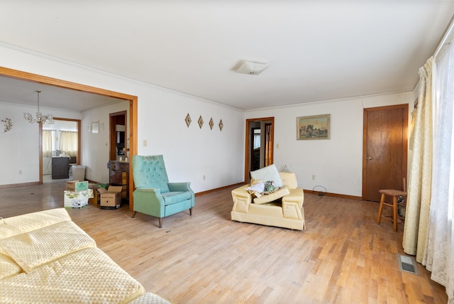 living room with an inviting chandelier, wood-type flooring, and ornamental molding