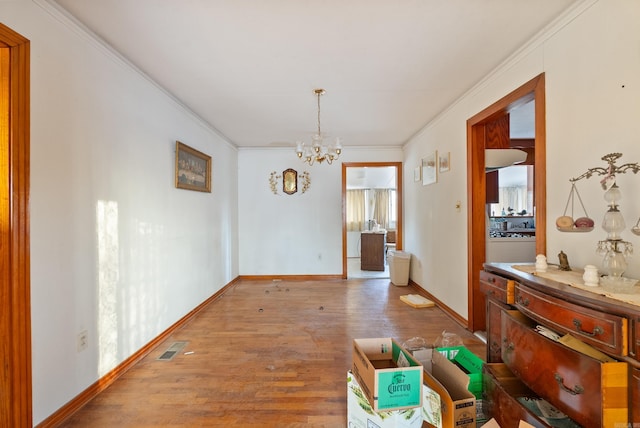 unfurnished dining area featuring hardwood / wood-style flooring, crown molding, and a chandelier