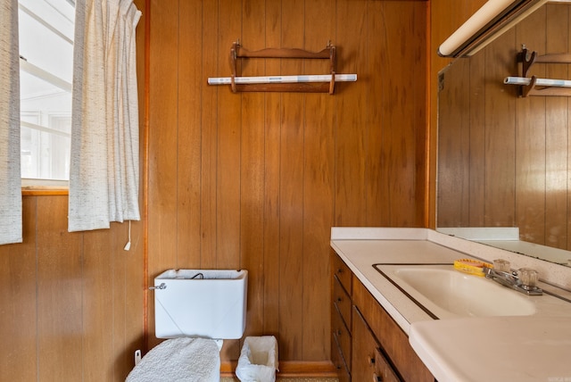 bathroom with toilet, vanity, and wood walls