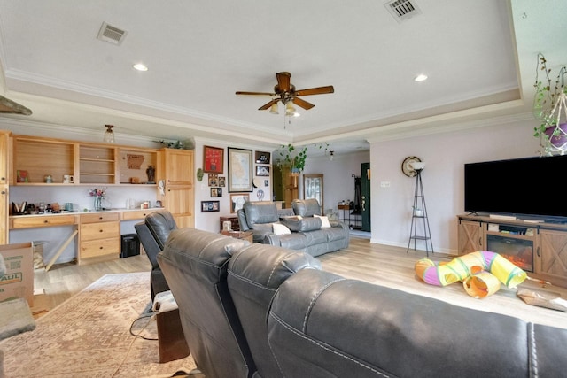 living room featuring crown molding, a tray ceiling, and light hardwood / wood-style flooring