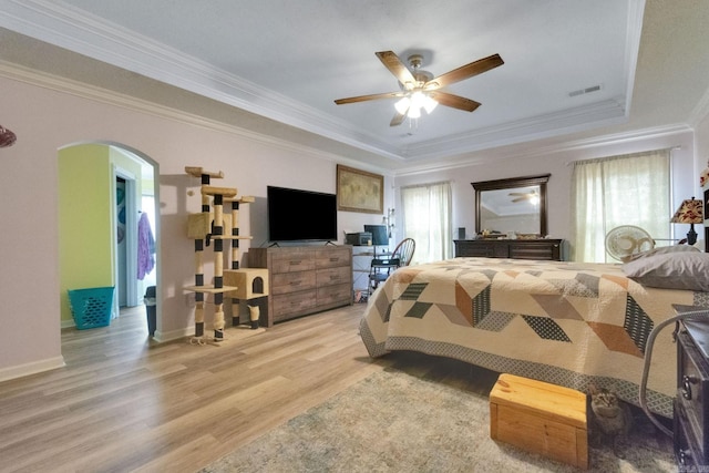 bedroom with crown molding, light hardwood / wood-style flooring, a raised ceiling, and ceiling fan